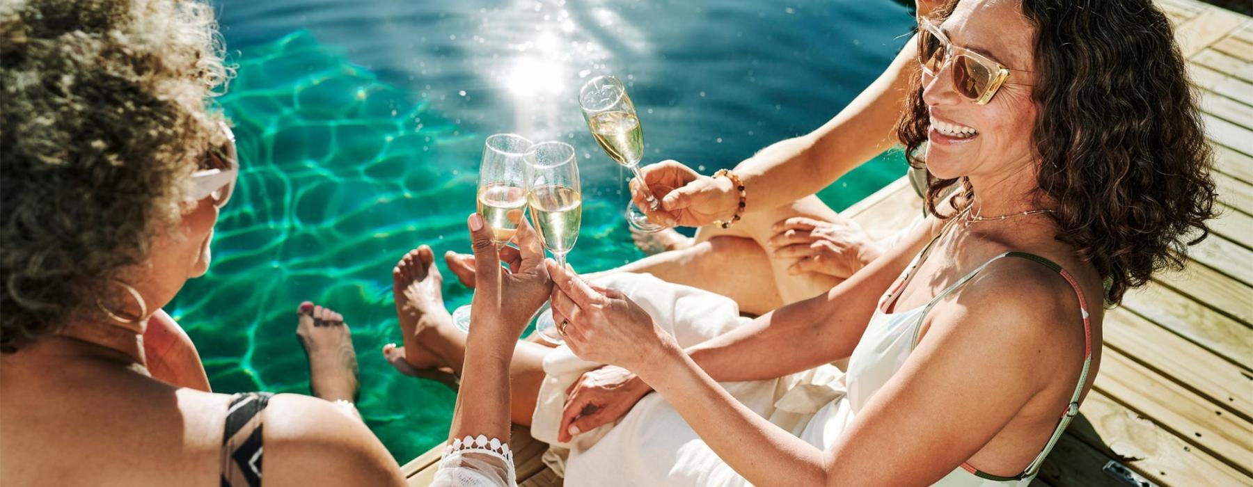 a group of women sitting by a pool with drinks